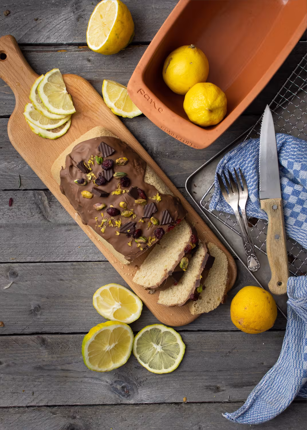 Römertopf längliche Brotbackschale mit Zitronen und Kuchen auf Holzbrett