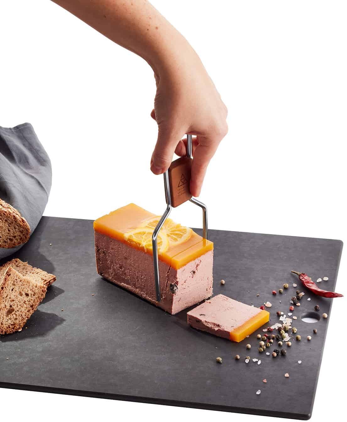triangle Käselyra schneidet Pastete auf Servierplatte mit Brot