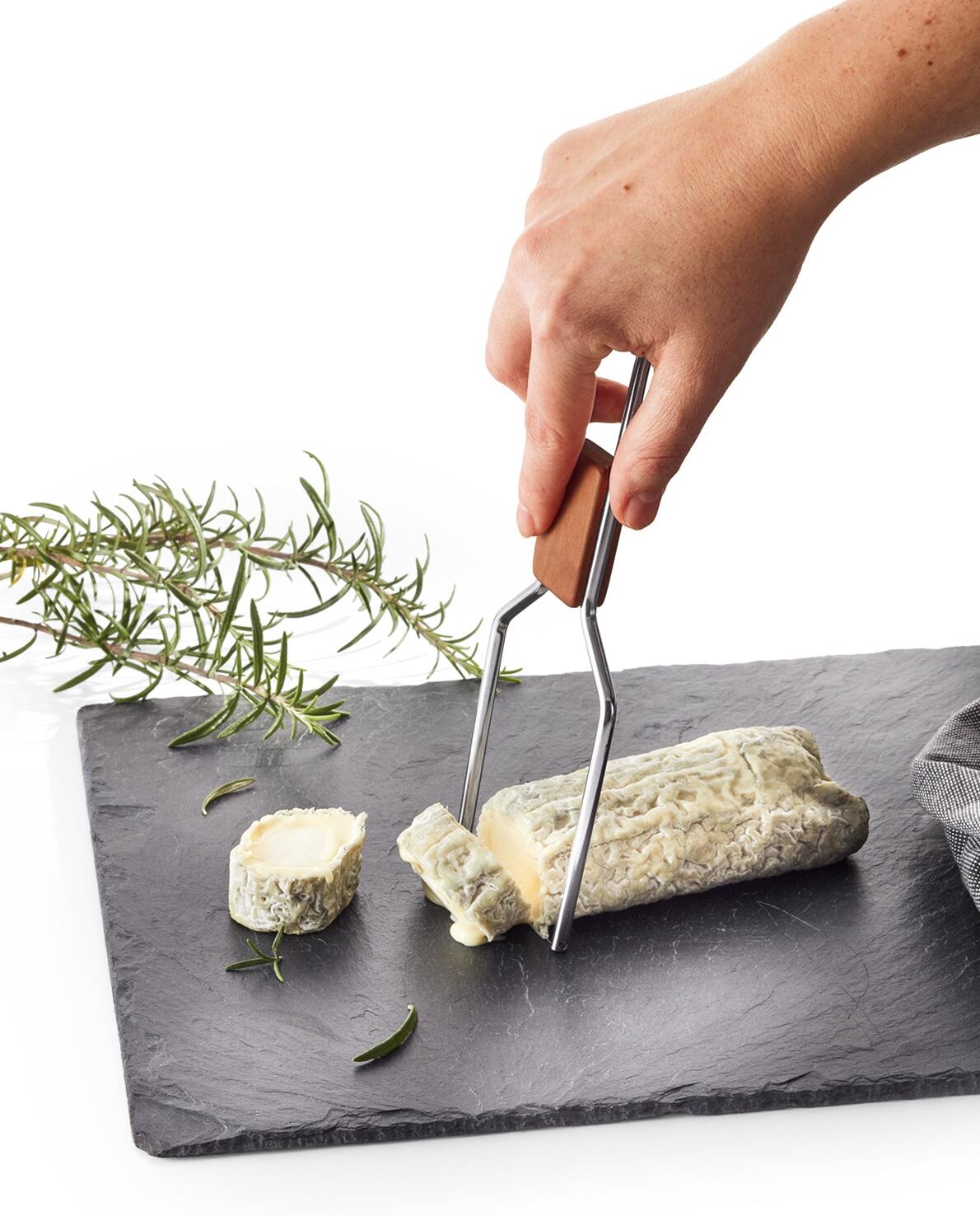triangle Käselyra schneidet Ziegenkäse auf Schieferplatte