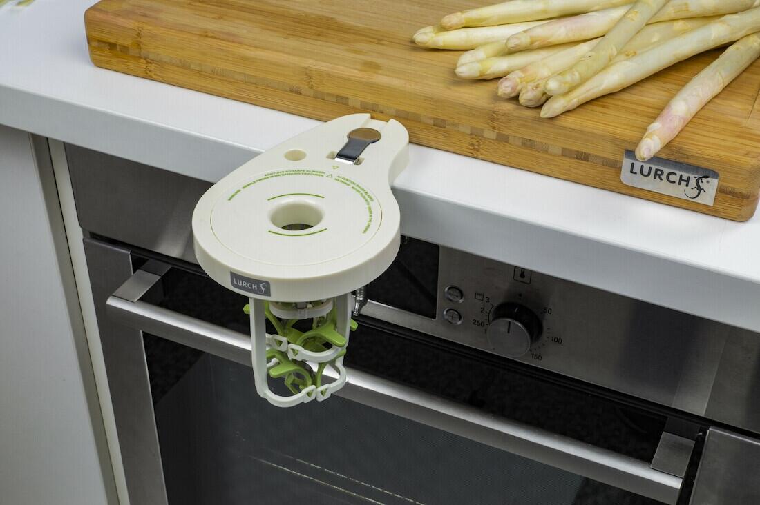 Lurch Spargelschäler grün am Ofengriff, Spargel auf Schneidebrett