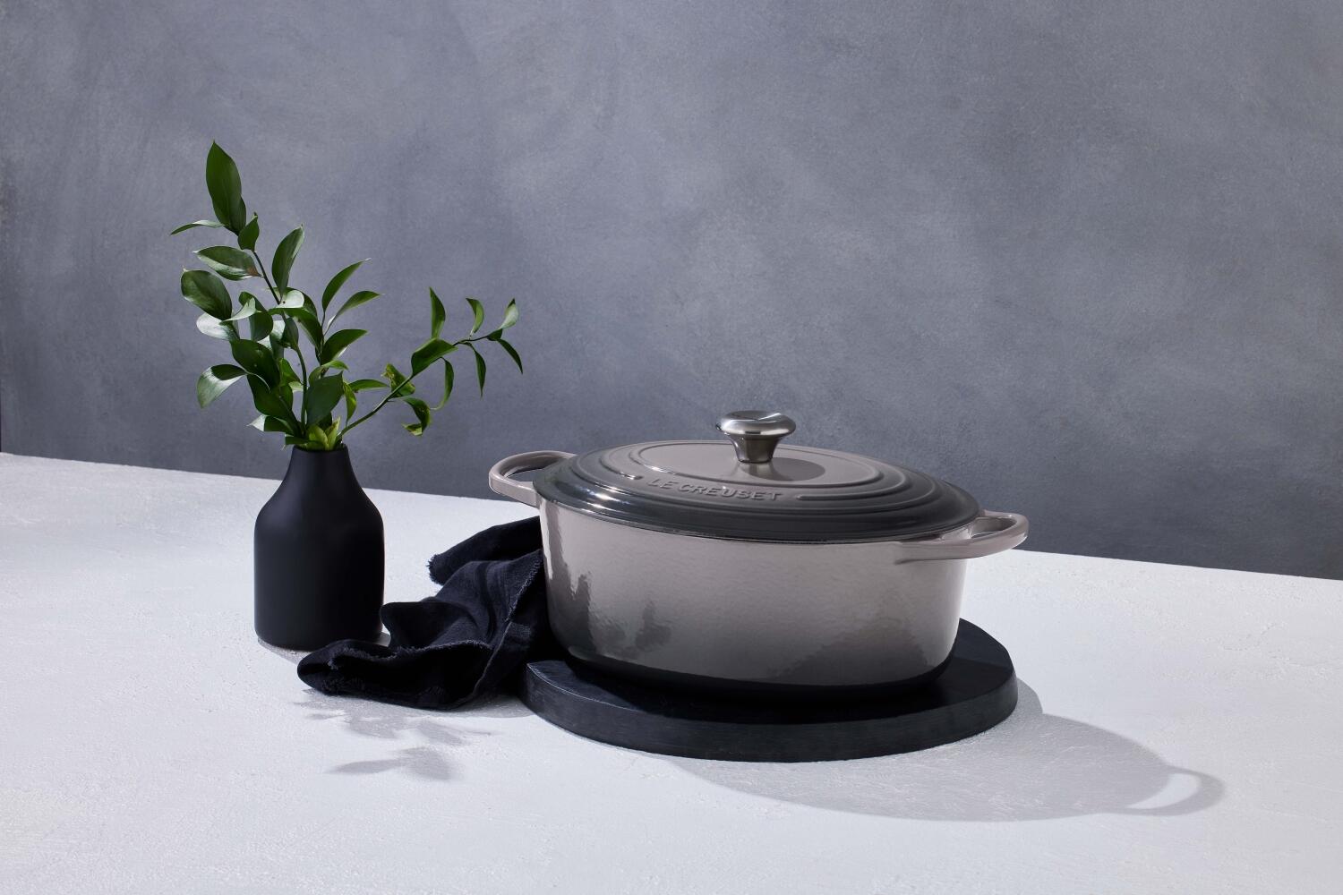 Le Creuset Signature ovaler Bräter flint mit Deckel auf Tisch