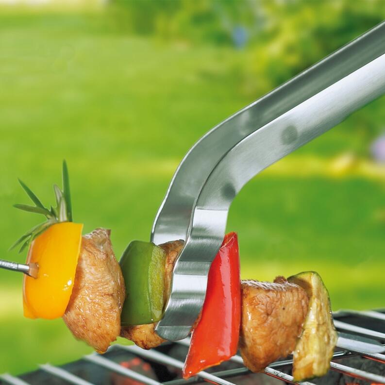 Rösle gebogene Grillzange greift Grillspieß mit Gemüse und Fleisch